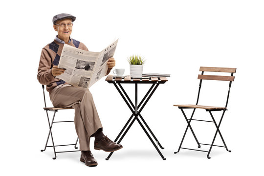 Mature man with a newspaper sitting at a coffee table