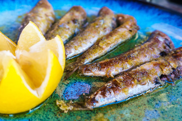 Fried sardines on a plate of lemon.