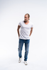 Full length of a cute young man in jeans and t-shirt looking at the camera, against white background.