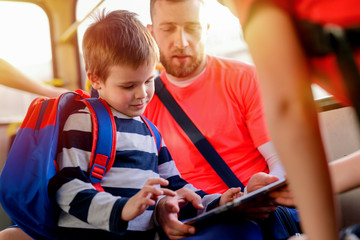 Close up of father and son sitting in a bus and looking at the tablet.