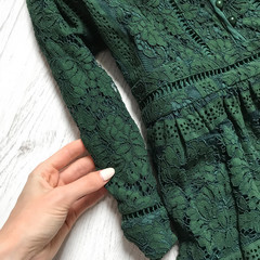 Green lace dress close up on wooden background