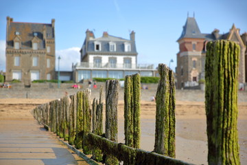 Colorful breakwaters located on Sillon beach with colorful house facades in the background, Saint Malo, Brittany, France