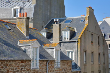 Close-up on traditional house facades with chimneys and roofs, located inside the walled city and...