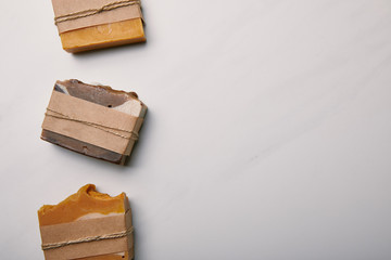 top view of row of various handmade soap pieces on white marble surface