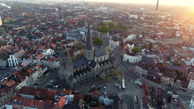 Flying over old european city at sunrise. Buildings and Cathedrals from above. Bruges, Belgium