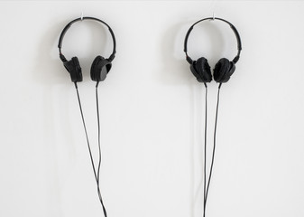 Modern black headphones hanging on white wall