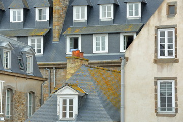 Obraz premium Close-up on traditional house facades with chimneys and roofs, located inside the walled city of Saint Malo, Brittany, France