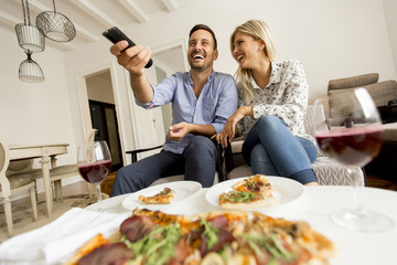 Young couple enjoying eating pizza and watching tv