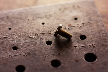 Right size. Finding the correct size or combination. Fitting. Old brass screw inserted in a screw...