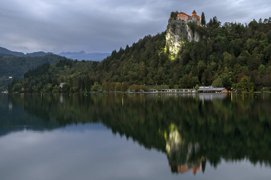 Beautiful mountain lake Bled . Night scenery at Bled lake in Slovenia.  usk scene on lake, illuminated  castle on hill.  Mountains in background. Slovenia, Europe. European travel.