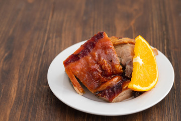 roasted piglet with orange on white plate
