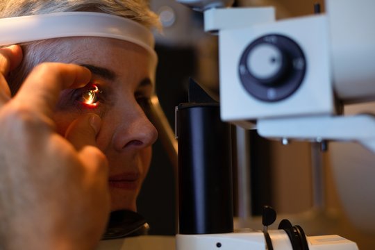 Optometrist examining patient eyes with slit lamp in clinic