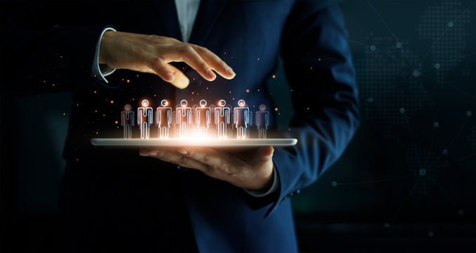 Businessman holding tablet and management group of people in his hand. Virtual icon of social network. Business technology concept.