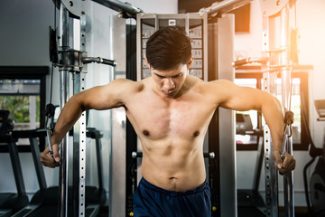 Athlete muscular bodybuilder training on simulator in the gym, strong male.