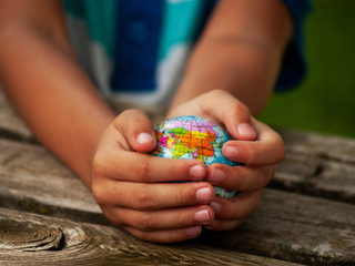 A boy with a ball of the world or planet Earth in his hands. Ecology concept