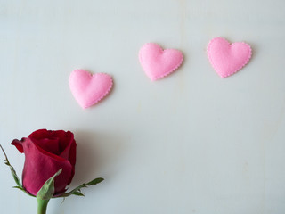 Red rose and pink hearts on white wood background