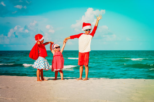 happy kids- little boy and girls- celebrating christmas on beach
