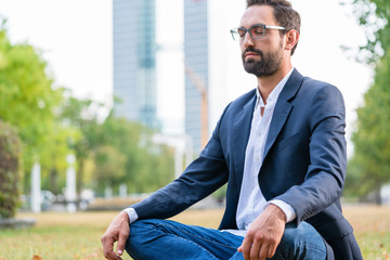 Close-up of calm businessman sitting in the park meditating