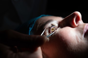 Optometrist examining patient eyes with eye test equipment in