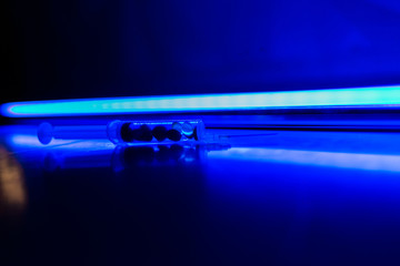 Drug syringe, narcotic dangerous concept,drug abuse.capsules, colored pills on a blue background,...