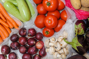 Various fruits and vegetables in plastic bags are on the floor in the house. Bought on the market