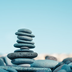 Stone cairn on green blurry background, pebbles and stones. Concept balance