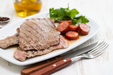 grilled meat with smoked sausage on white dish