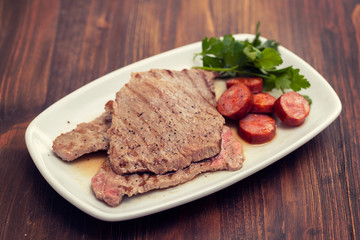 grilled meat with smoked sausage on white dish