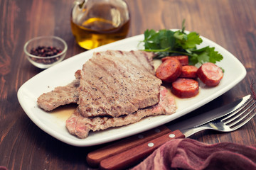 grilled meat with smoked sausage on white dish