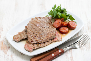 grilled meat with smoked sausage on white dish