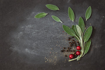 Fototapeta Leaves of fresh sage, black ceg peas on a dark background obraz