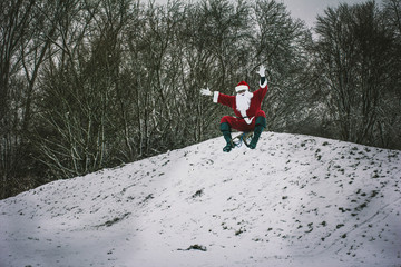 Santa Claus sledging in a snow-covered winter park. Santa Claus greet and waving his hands.