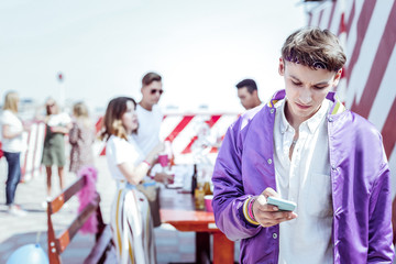 Fototapeta premium So sad. Negative delighted male person bowing head while reading message on telephone