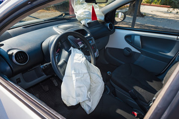 Interior of crashed car after accident with deflated airbags on road in city, sunny day
