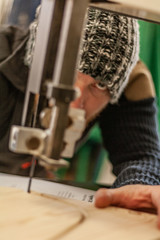 Eco friendly woodworker's shop. Details and focus on the young worker, while making legs for a designer coffee table. Mastering wood with peacefullness.