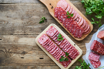 Sliced salami with parsley on a wooden cutting board