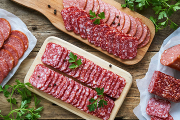 Sliced salami with parsley on a wooden cutting board