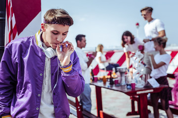 Have a look. Attentive student leaning on wall while smoking cigarette