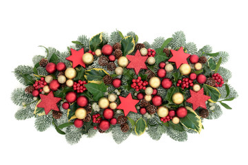 Christmas and winter table decoration with red and gold bauble decorations, holly berries, spruce pine, ivy, pine cones and mistletoe isolated on white background.