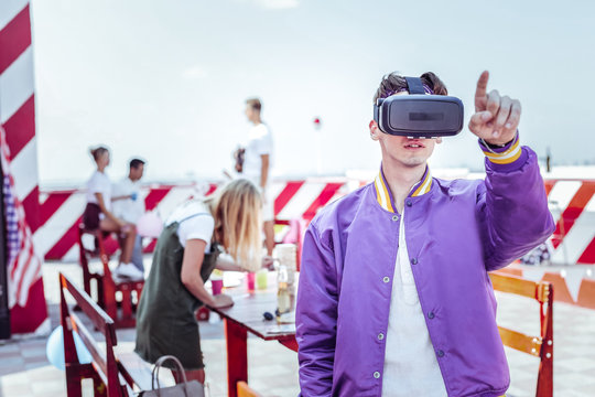 Virtual reality. Young man wearing electronic mask while pointing at something strange