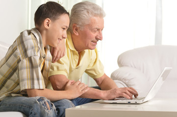 Grandfather with grandson using laptop at home