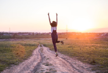 happy girl jumping on the road at the sunset