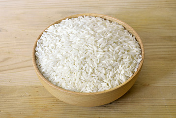 Raw, parboiled rice in a wooden bowl. Rice dish on a wooden table, diet or healthy eating scene.