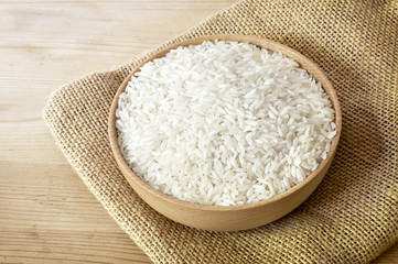 Raw, parboiled rice in a wooden bowl. Rice dish on a wooden table, diet or healthy eating scene.
