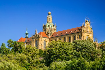 Fototapeta na wymiar Monumental monastery of Benedictines in Kladruby, Czech Republic, Europe from 12th century standing on hill, includes church of All Saints, red roof, green foreground, sunny summer day, blue sky