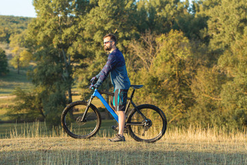 Naklejka premium A cyclist rides the hills, Beautiful portrait of a guy on a blue bicycle 
