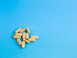 Assorted size and shape yellow pills on a blue background