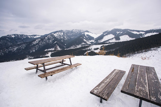 Jasna ski resort. Amazing view from the wooden table and benches to  mountains tops in the foggy sky . Low Tatras mountains, Slovakia.