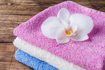 Obraz na płótnie Canvas Spa and Wellness concept on wooden background. Colorful Terry towels and a white Orchid flower.