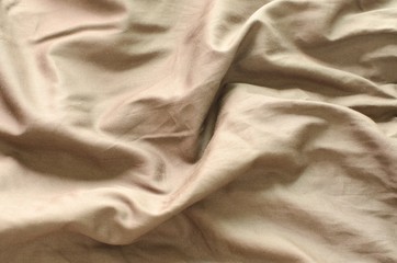 Top view of messy brown color bed sheet texture background.